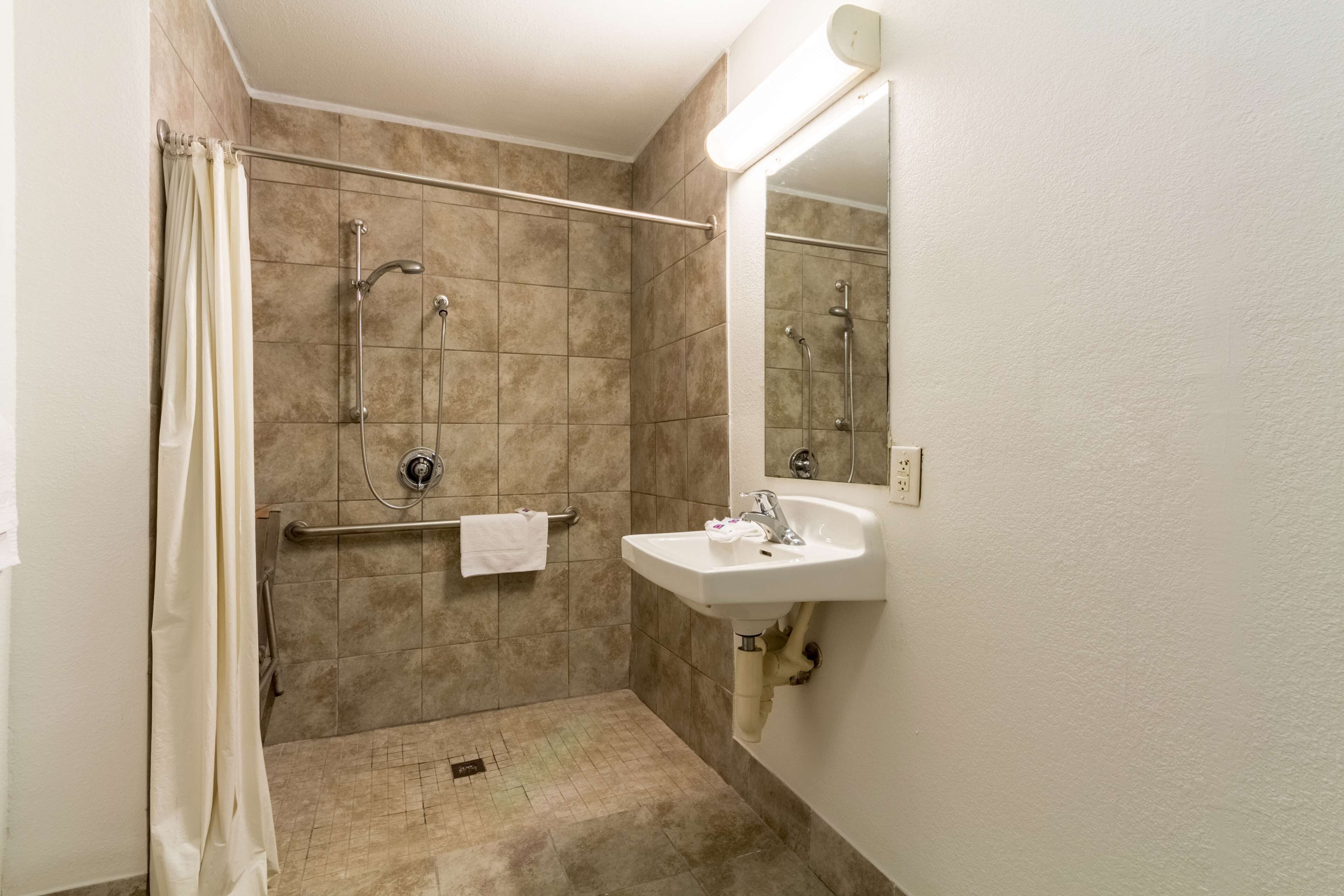 A bathroom with a shower, a sink, and a mirror.
