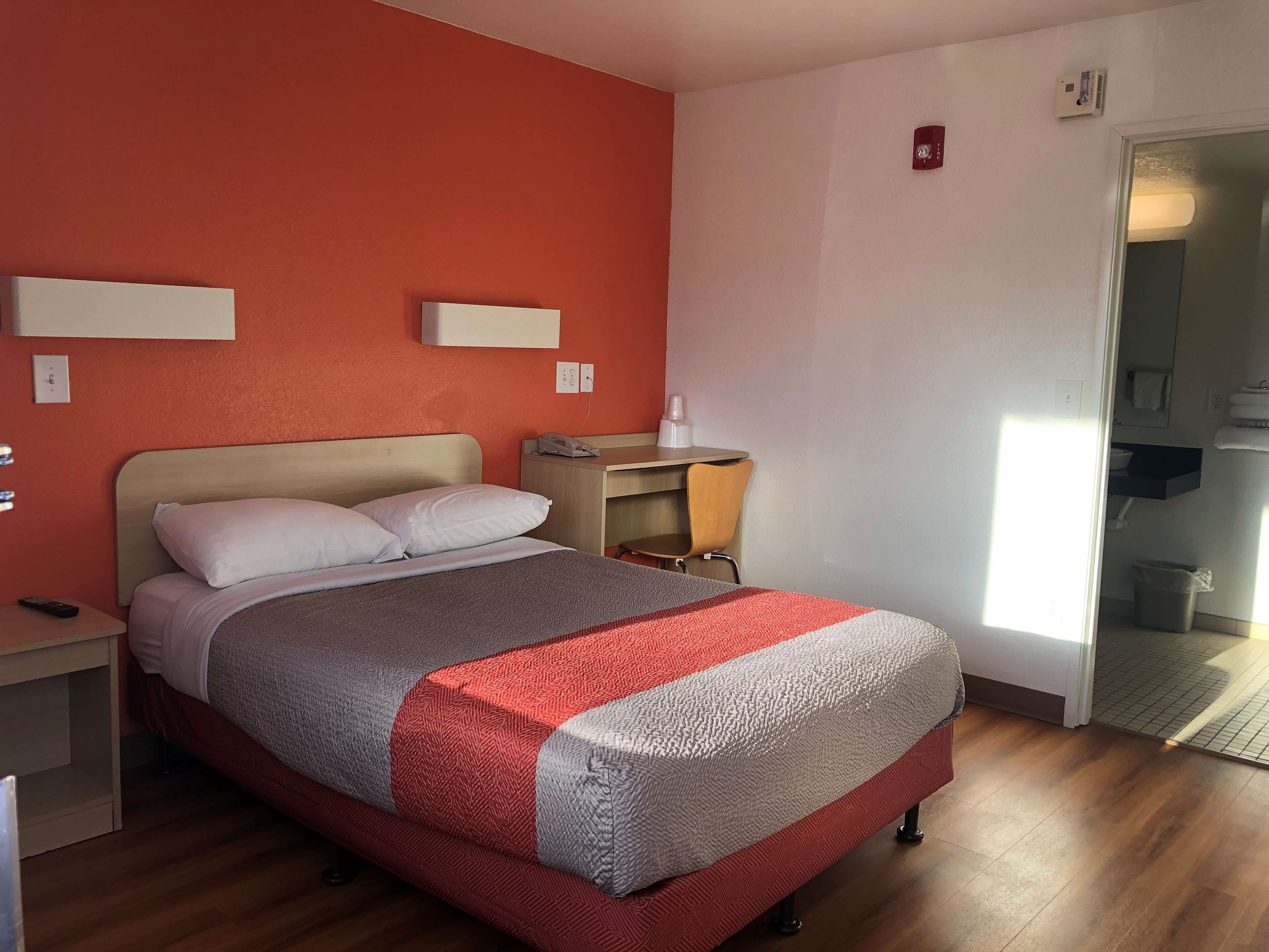 Une chambre d’hôtel avec un lit, une table de chevet et un bureau avec une chaise.