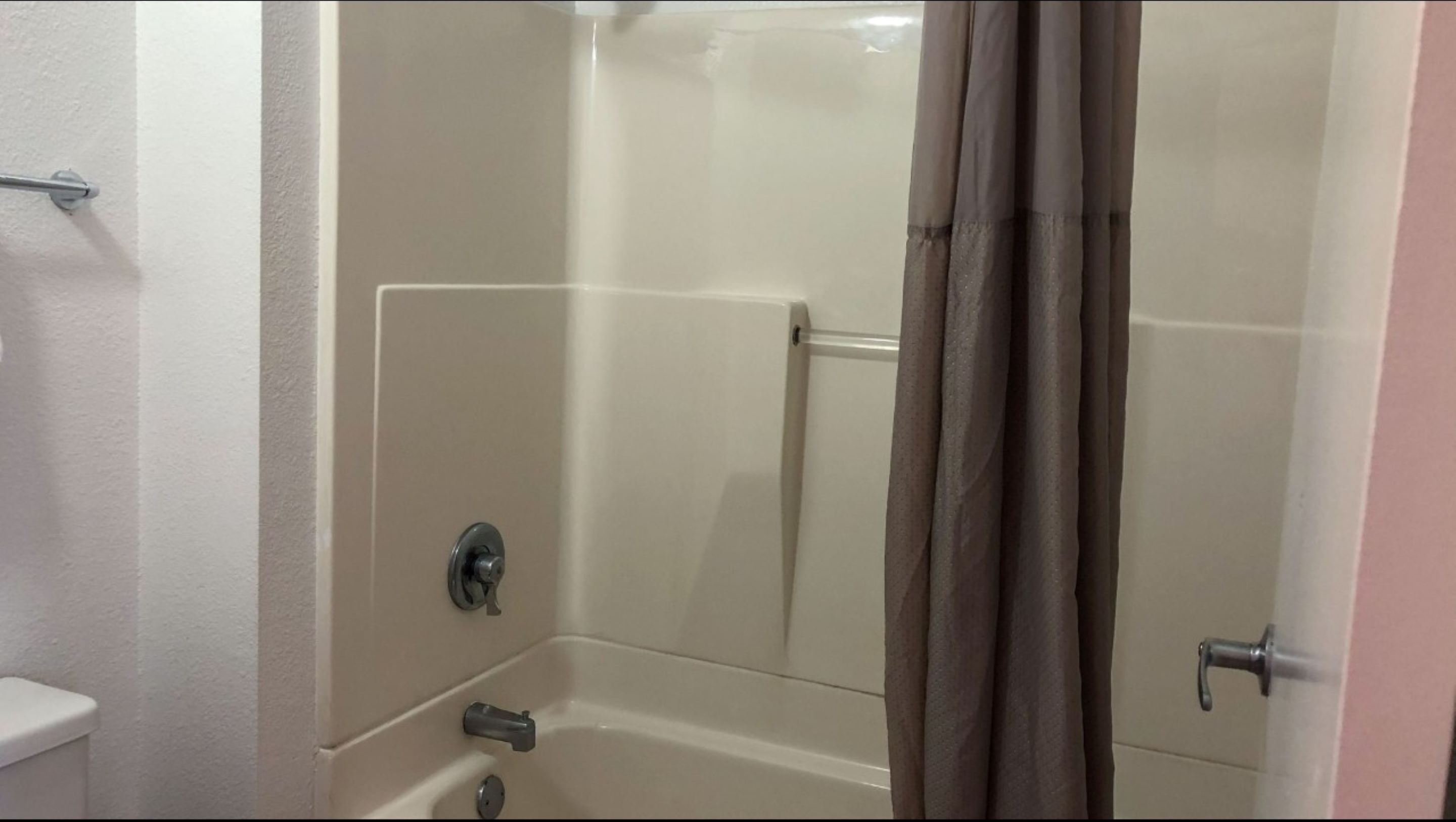 A bathroom with a bathtub, a toilet, and a shower curtain.