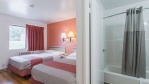 Habitación de hotel con dos camas, ducha y ventana con cortinas.