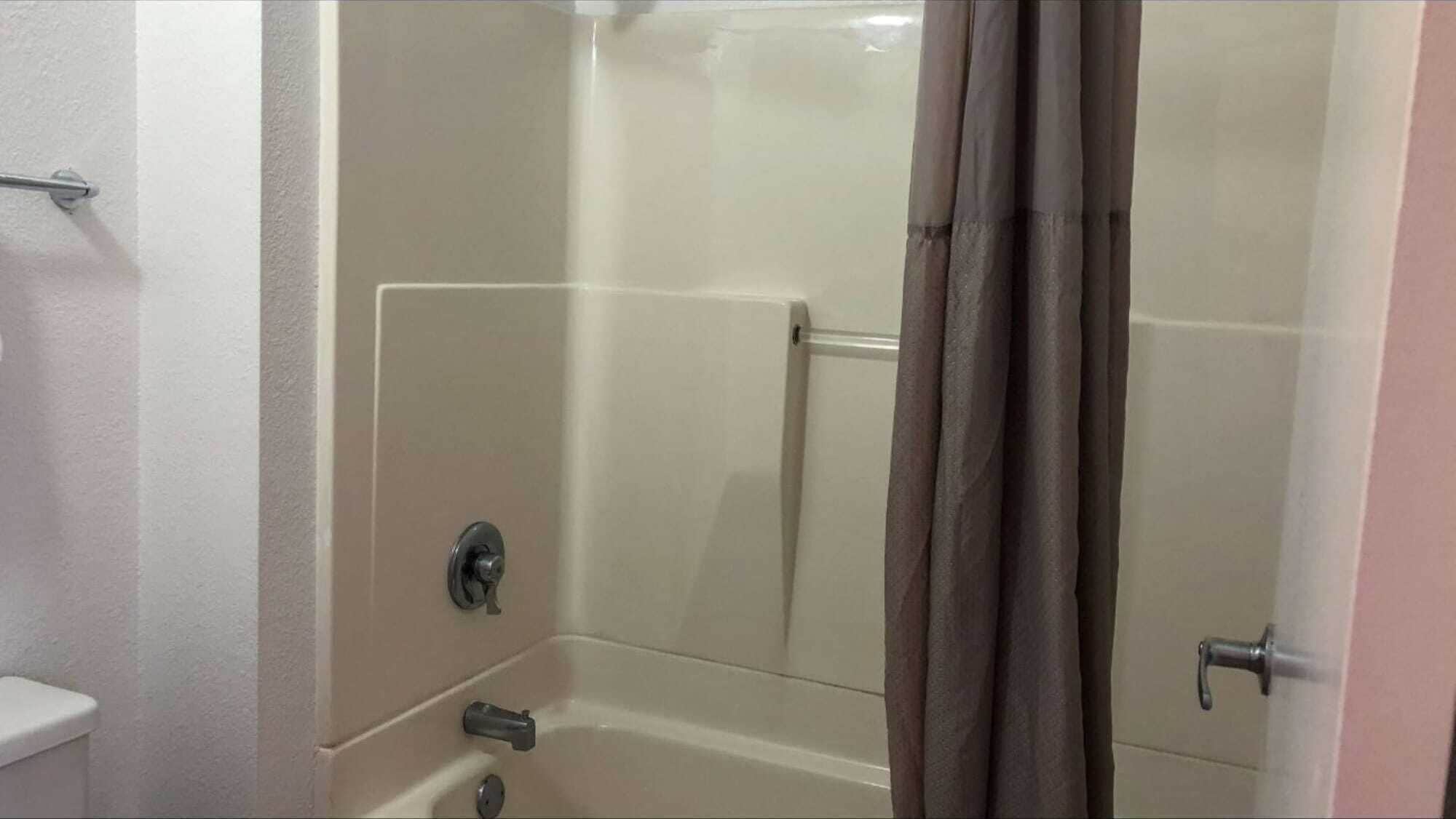 A bathroom with a bathtub, a toilet, and a shower curtain.