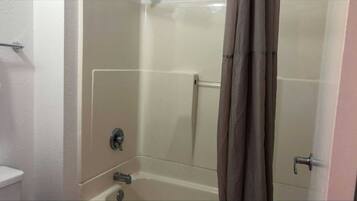 A bathroom with a bathtub, a toilet, and a shower curtain.