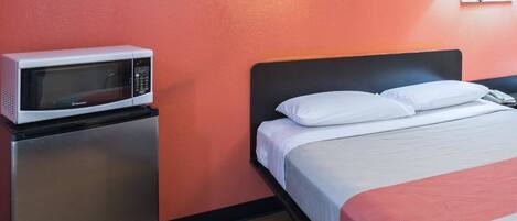 Quarto de hotel com uma cama, micro-ondas e frigorífico.