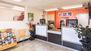 Un espace d’accueil comprenant un comptoir, deux écrans d’ordinateur, une horloge et un mur orné de tableaux et d’une affiche.