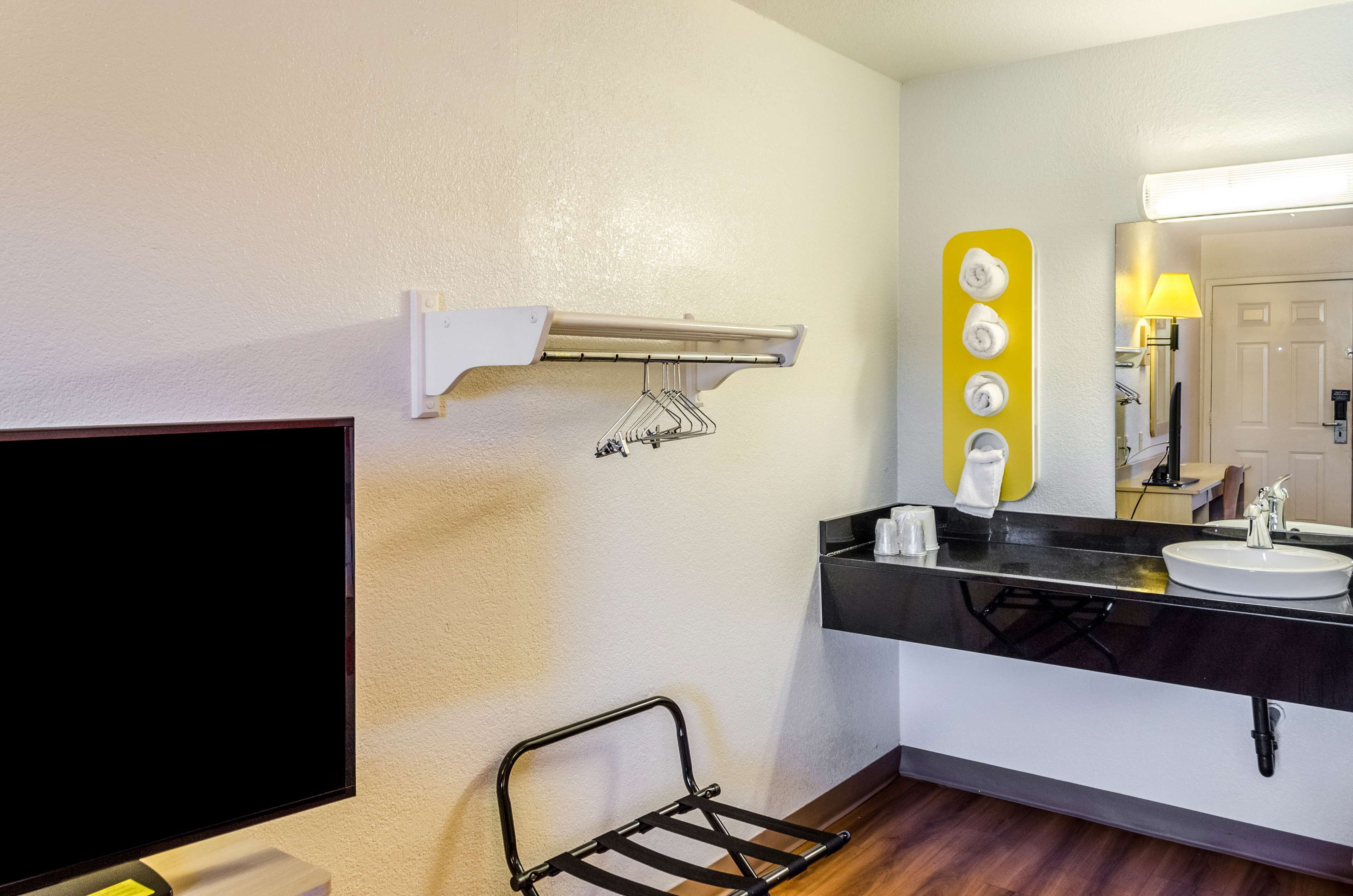 A modern bathroom with a black vanity, a white sink, a mirror with a yellow accent, a towel rack, and a wall-mounted heater.