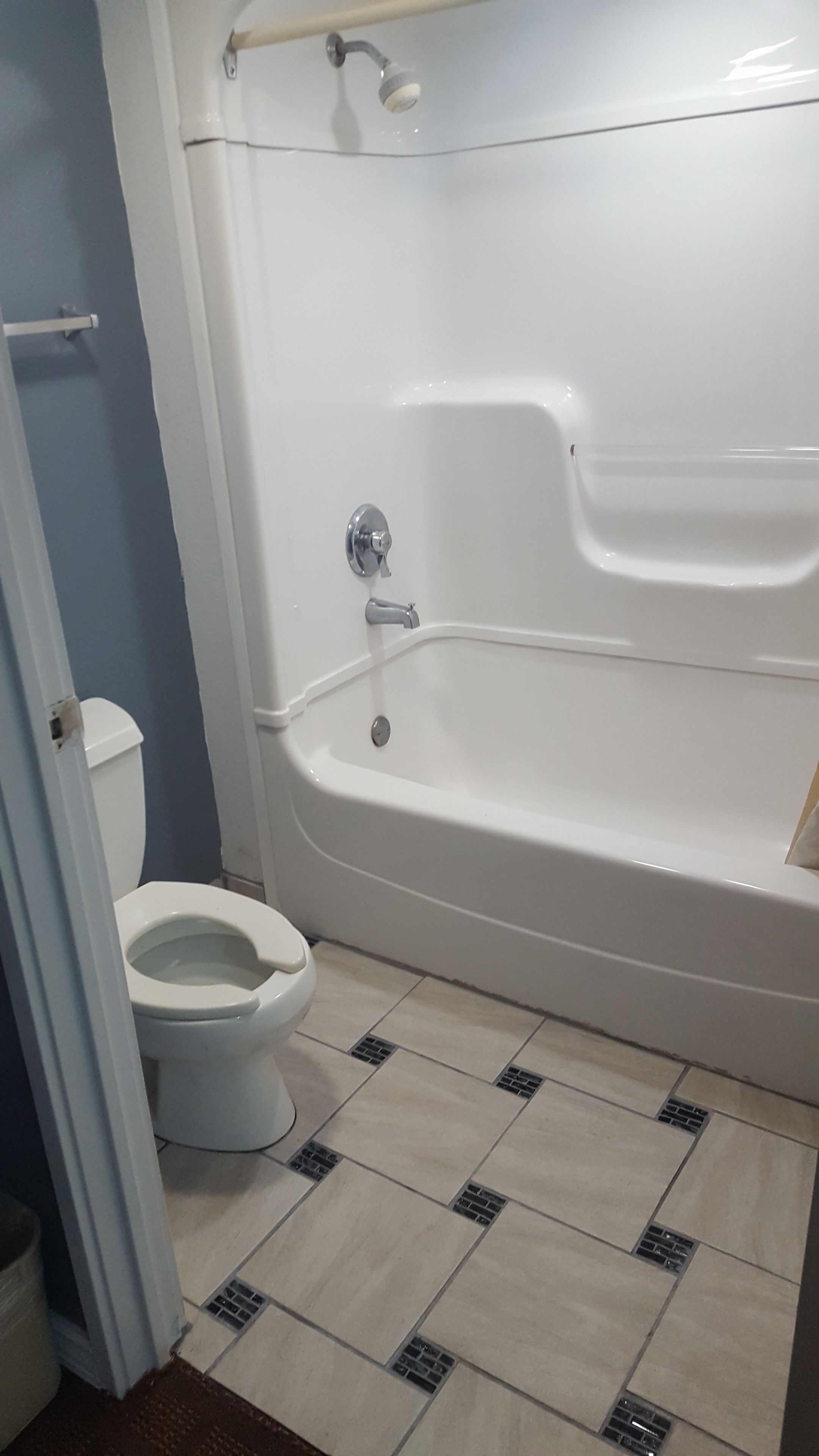 A bathroom with a bathtub, toilet, and tiled floor.