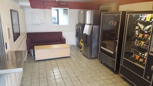Eine kleine Küchenzeile mit Kühlschrank, Getränkeautomaten und einer Sitzecke.
