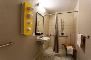Un baño pequeño con lavamanos, espejo y ducha.