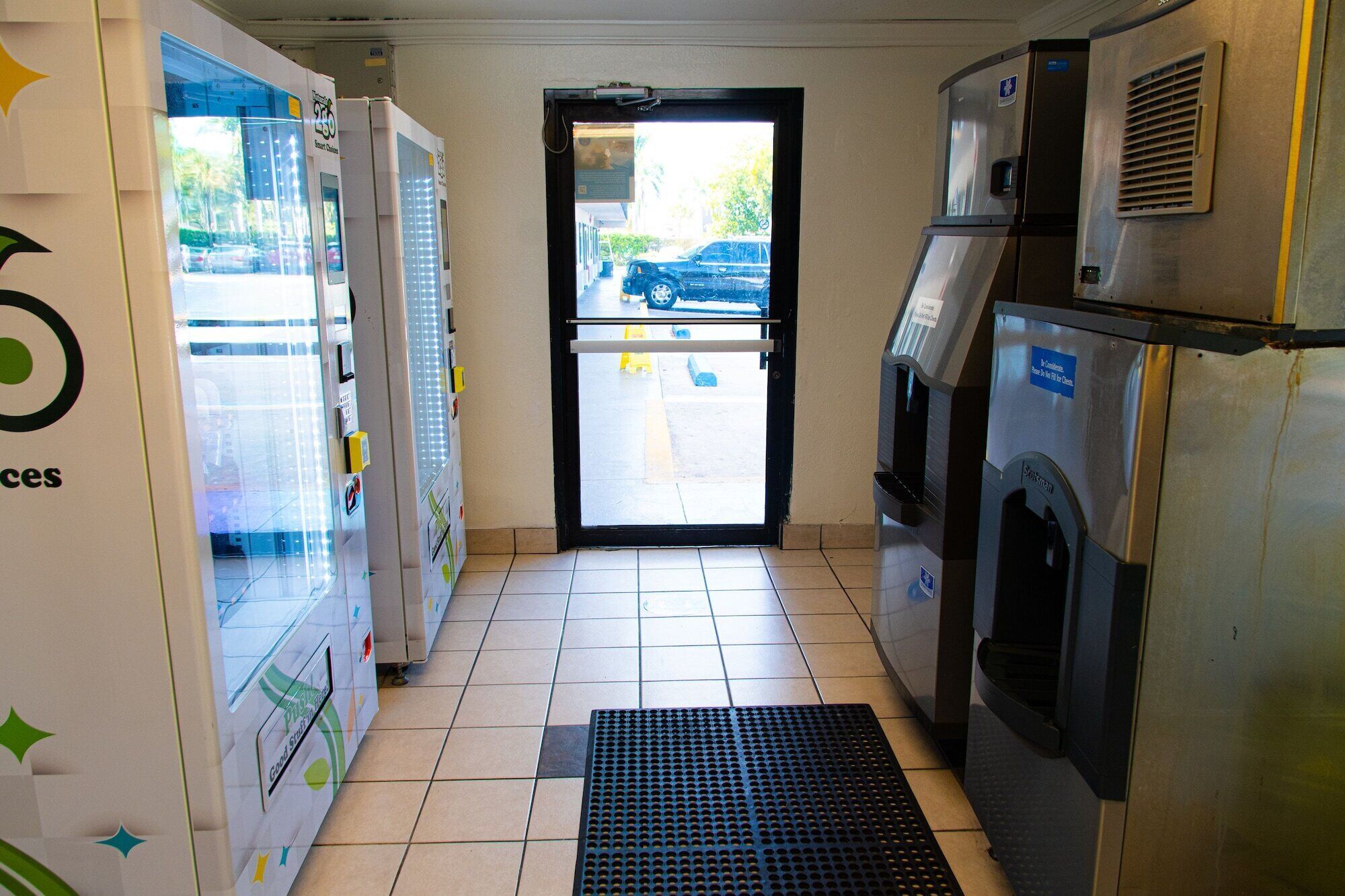 Spazio commerciale con distributori automatici, una porta che dà sull'esterno e un cestino per i rifiuti.