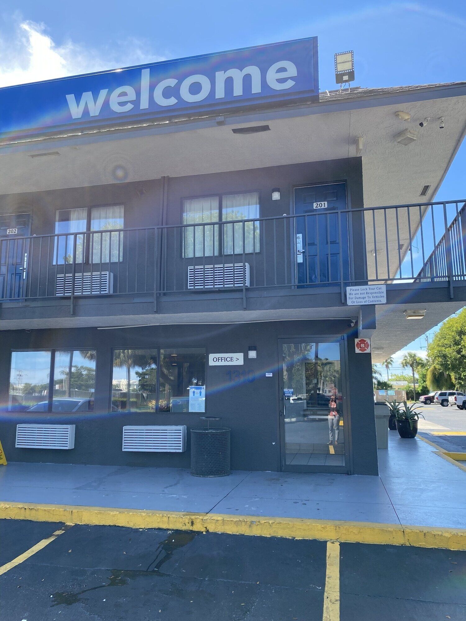 Un edificio con un letrero de 'welcome', una oficina en la planta baja y un balcón con barandillas.