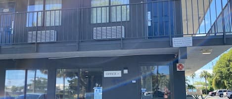 Un edificio con un letrero de 'welcome', una oficina en la planta baja y un balcón con barandillas.