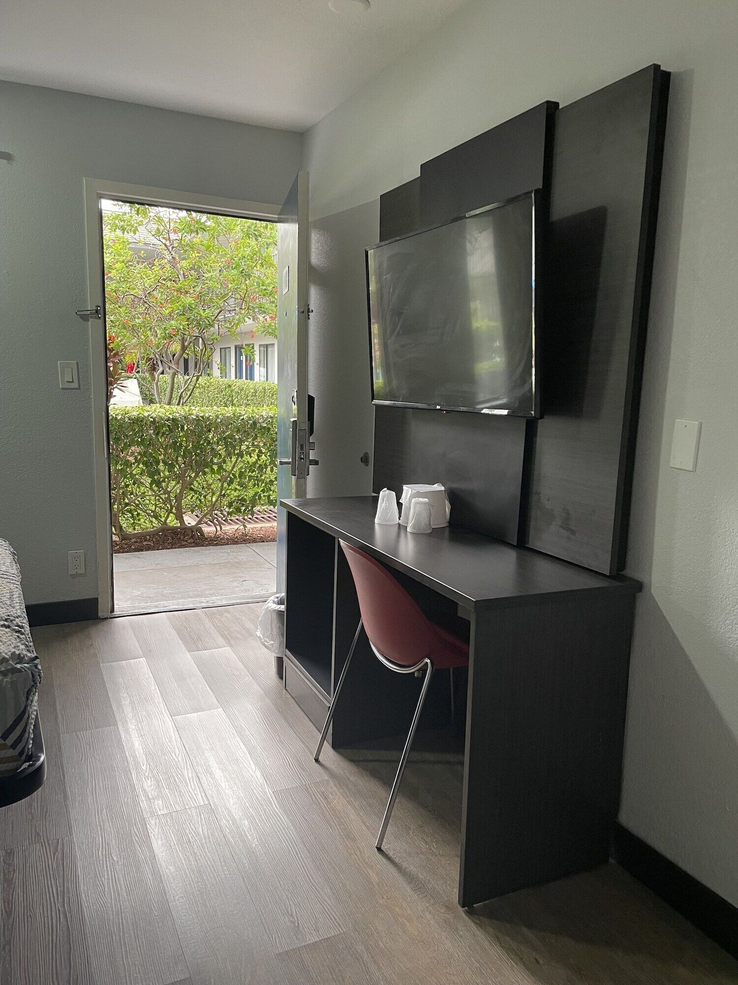 A modern room with a dark desk, a red chair, and a flat-screen TV mounted on the wall.