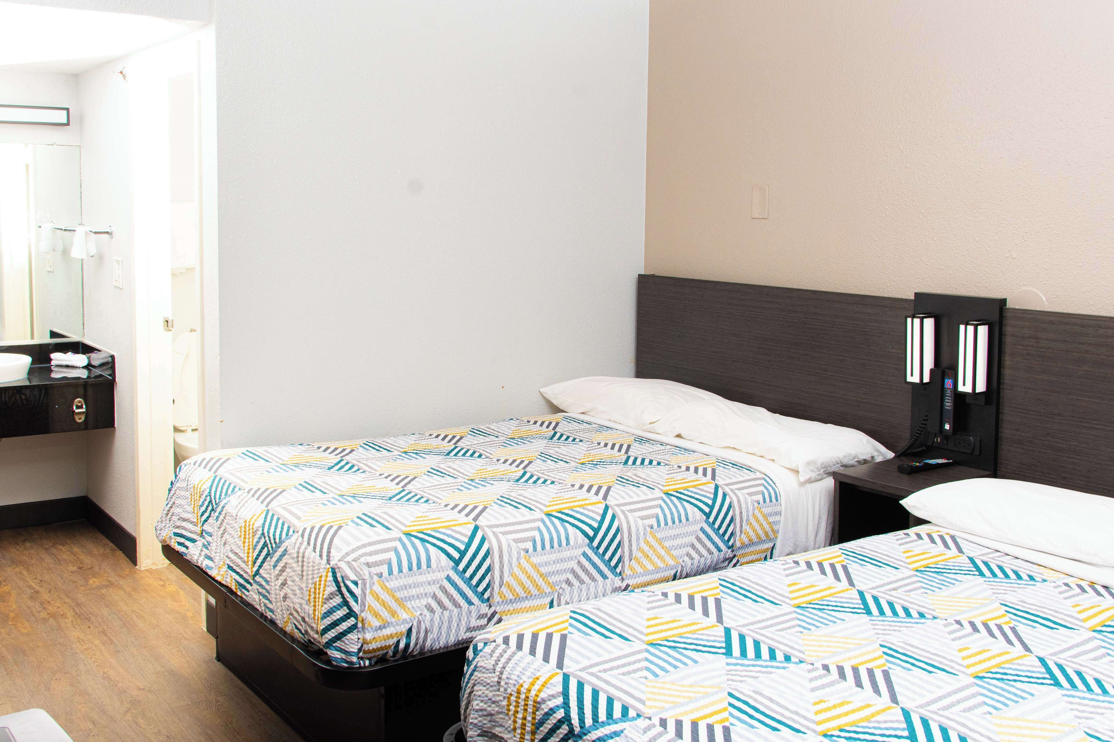 A hotel room with two beds, a bedside table, a mirror, and a wardrobe.