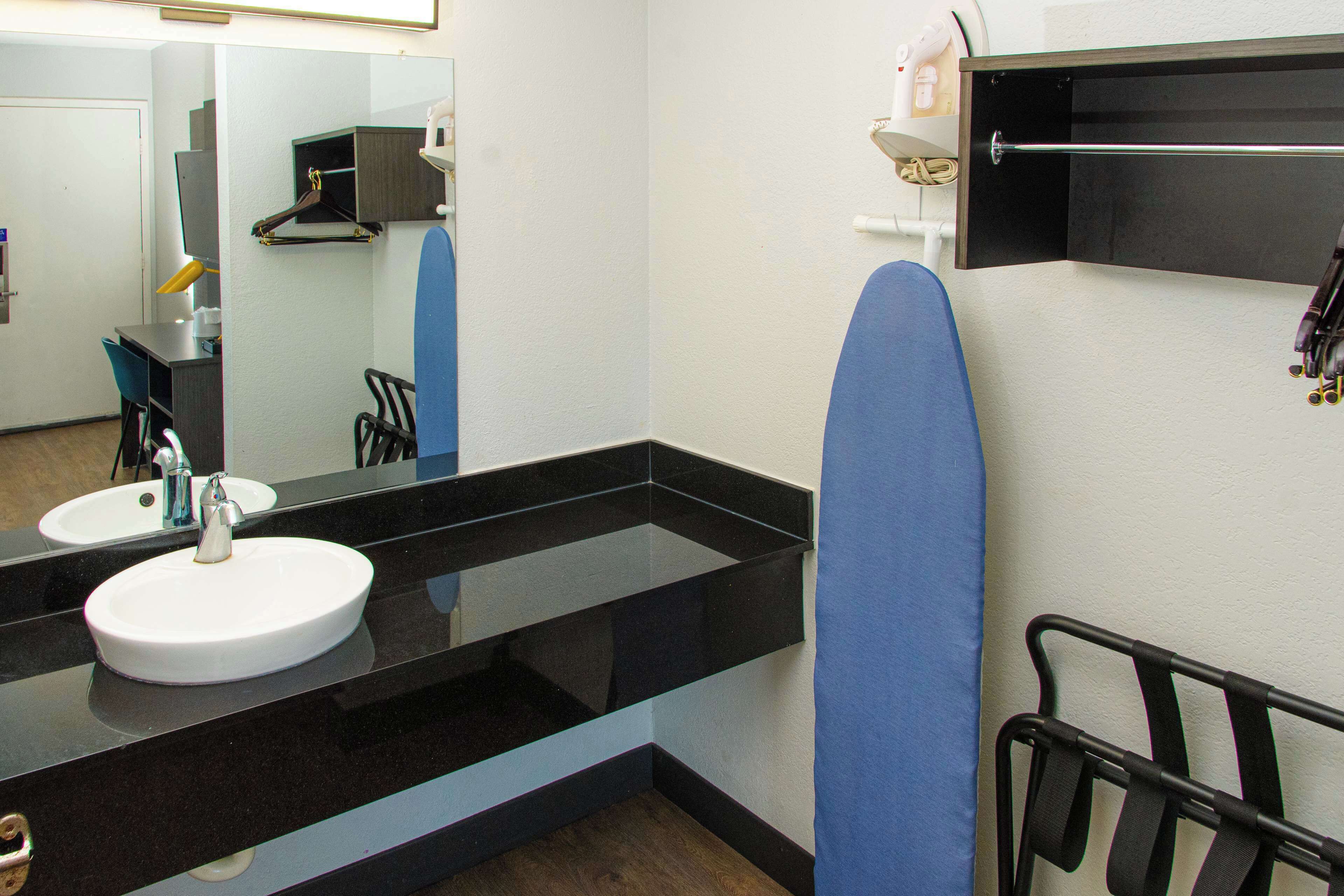 A modern bathroom with a black countertop, a white sink, and a mirror.