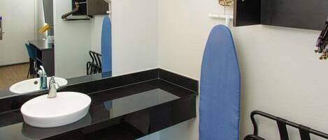 A modern bathroom with a black countertop, a white sink, and a mirror.