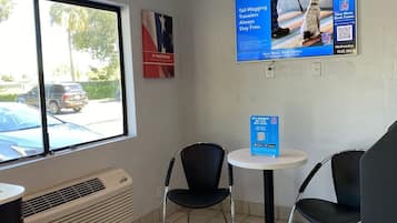 A small, clean room with a window, two chairs, a table, and a poster on the wall.