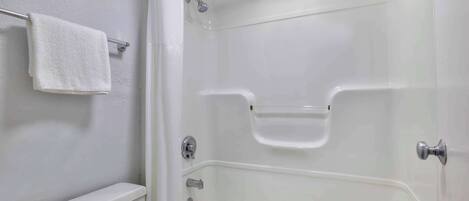 A bathroom with a white toilet, a glass-enclosed shower, and a white towel hanging on a metal rack.