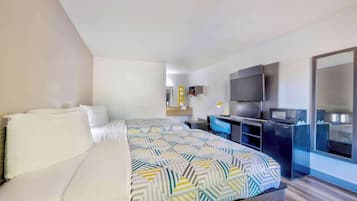 Ein modernes Hotelzimmer mit Bett, Schreibtisch, Fernseher und großem Spiegel.