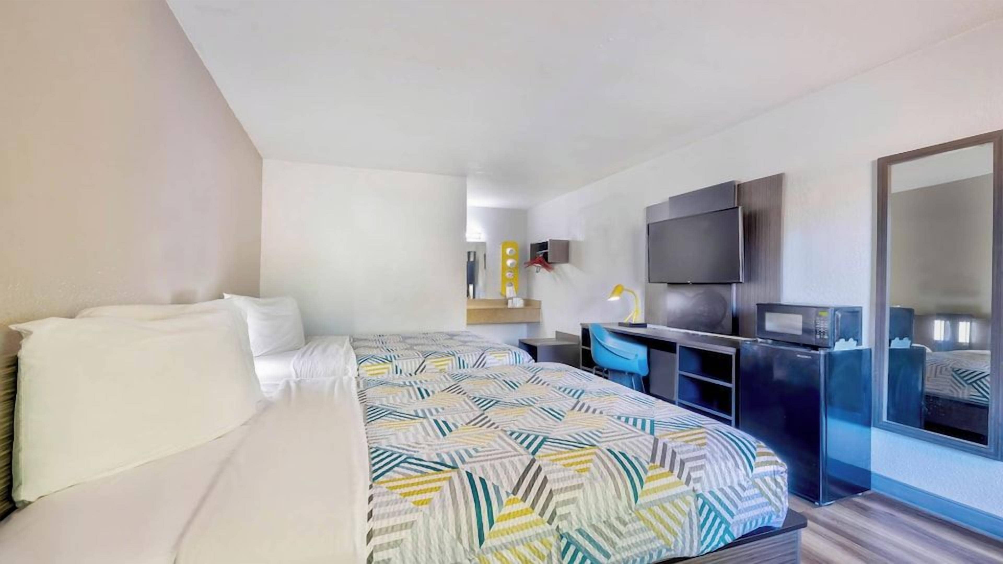A hotel room with a bed, a desk, a television, and a mirror.