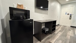 A compact kitchenette with a microwave, refrigerator, and a small desk. - Motel 6 Tacoma, WA - South (Tacoma)