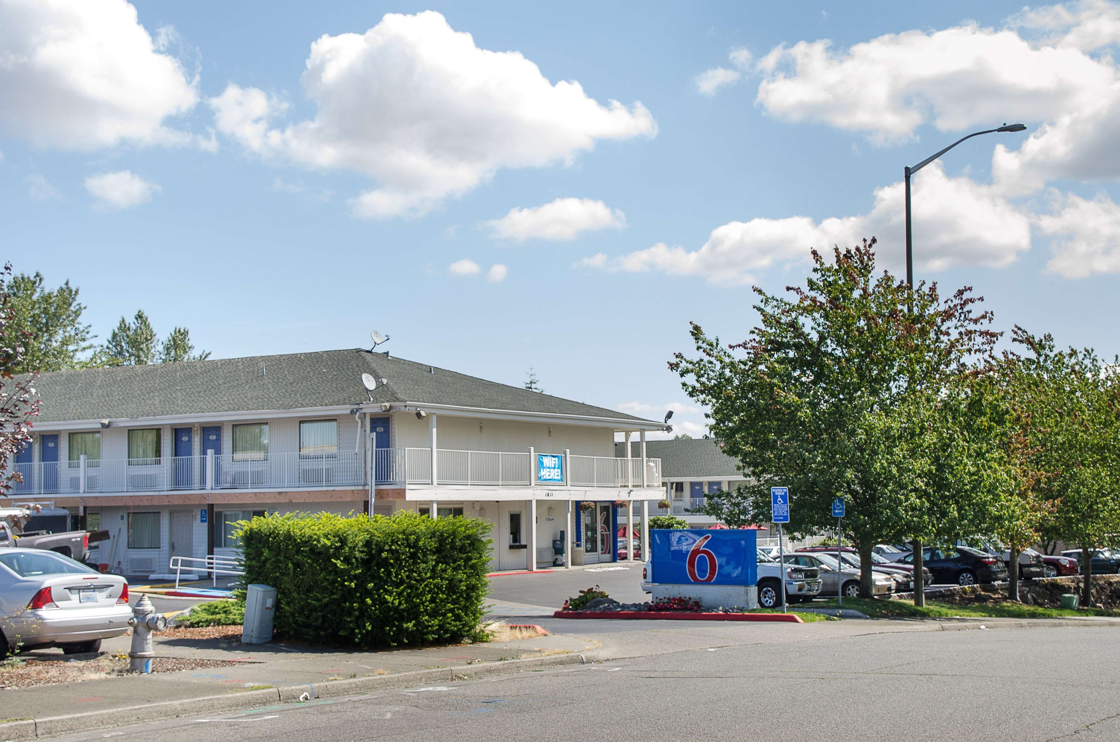 A motel with a two-story structure, a parking lot, and a sign indicating room number 6.