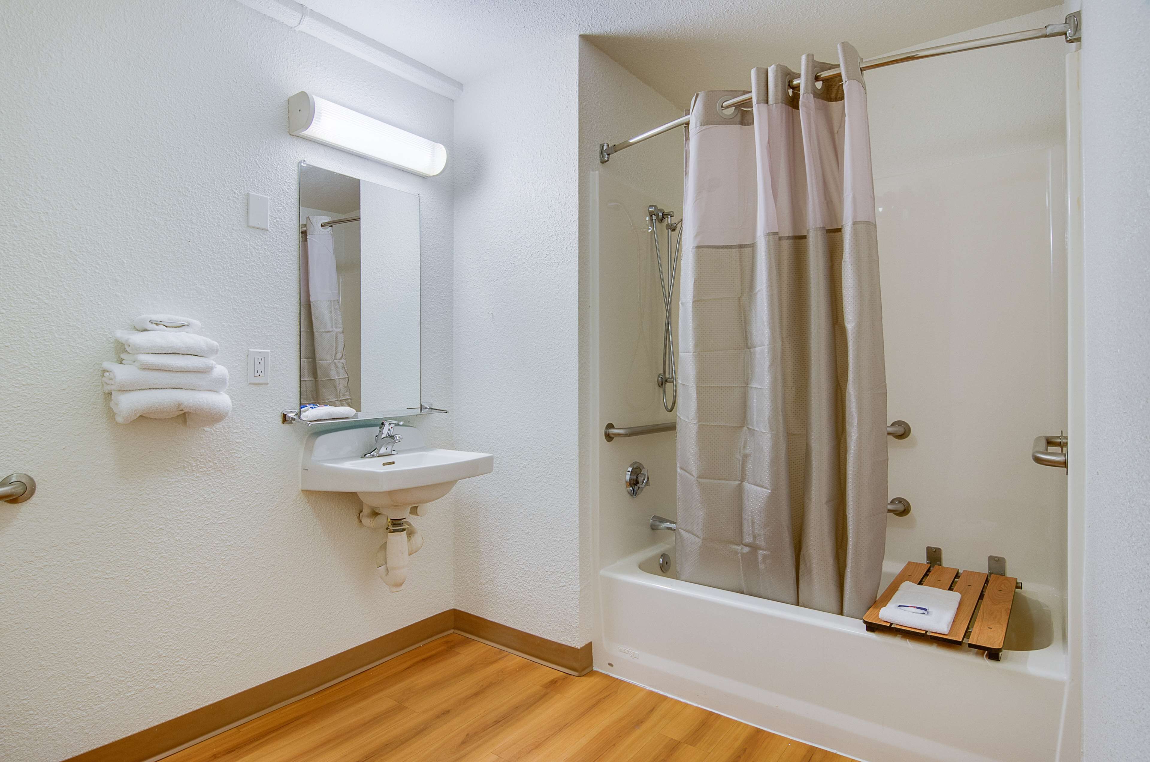 Un baño con lavamanos, espejo, toallero y ducha con puerta de vidrio.