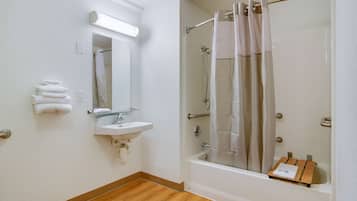 Un baño con lavamanos, espejo, toallero y ducha con puerta de vidrio.