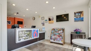 A reception area with a counter, a clock, a television, and a bulletin board with flyers. - Motel 6 Tacoma, WA - South (Tacoma)
