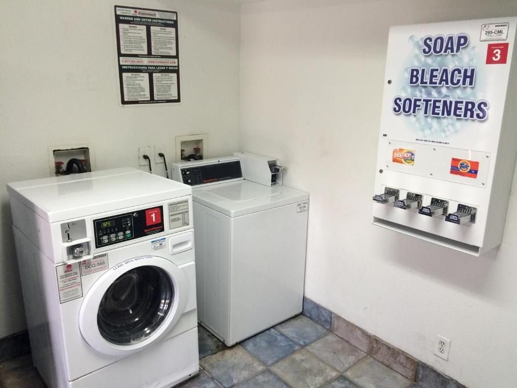 Une buanderie équipée d’un lave-linge, d’un sèche-linge et d’un distributeur de lessive, d’eau de Javel et d’adoucissant.