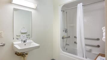 Un baño con lavamanos, espejo y ducha envuelta en vidrio con cortina.