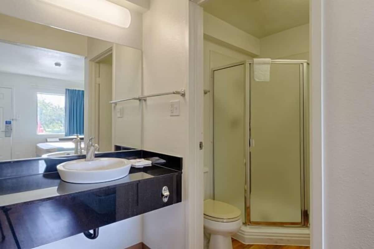 Un baño con lavamanos, espejo y ducha.