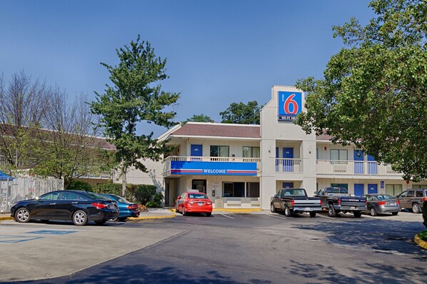 A motel with a '6' sign, a 'Welcome' sign, and a parking lot with several cars. - Motel 6 Laurel, DC - Washington Northeast (Laurel)