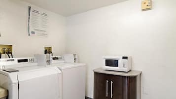 A laundry area with a washing machine, dryer, and microwave on a cabinet.