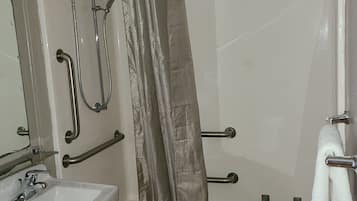 Un baño con bañera, ducha, lavamanos y un perchero para toallas.