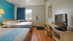 Une chambre d’hôtel avec deux lits, un bureau avec une télévision, une fenêtre avec des rideaux et une porte.