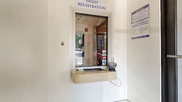 A night registration desk with a sign above it, a payment terminal, and a notice board.