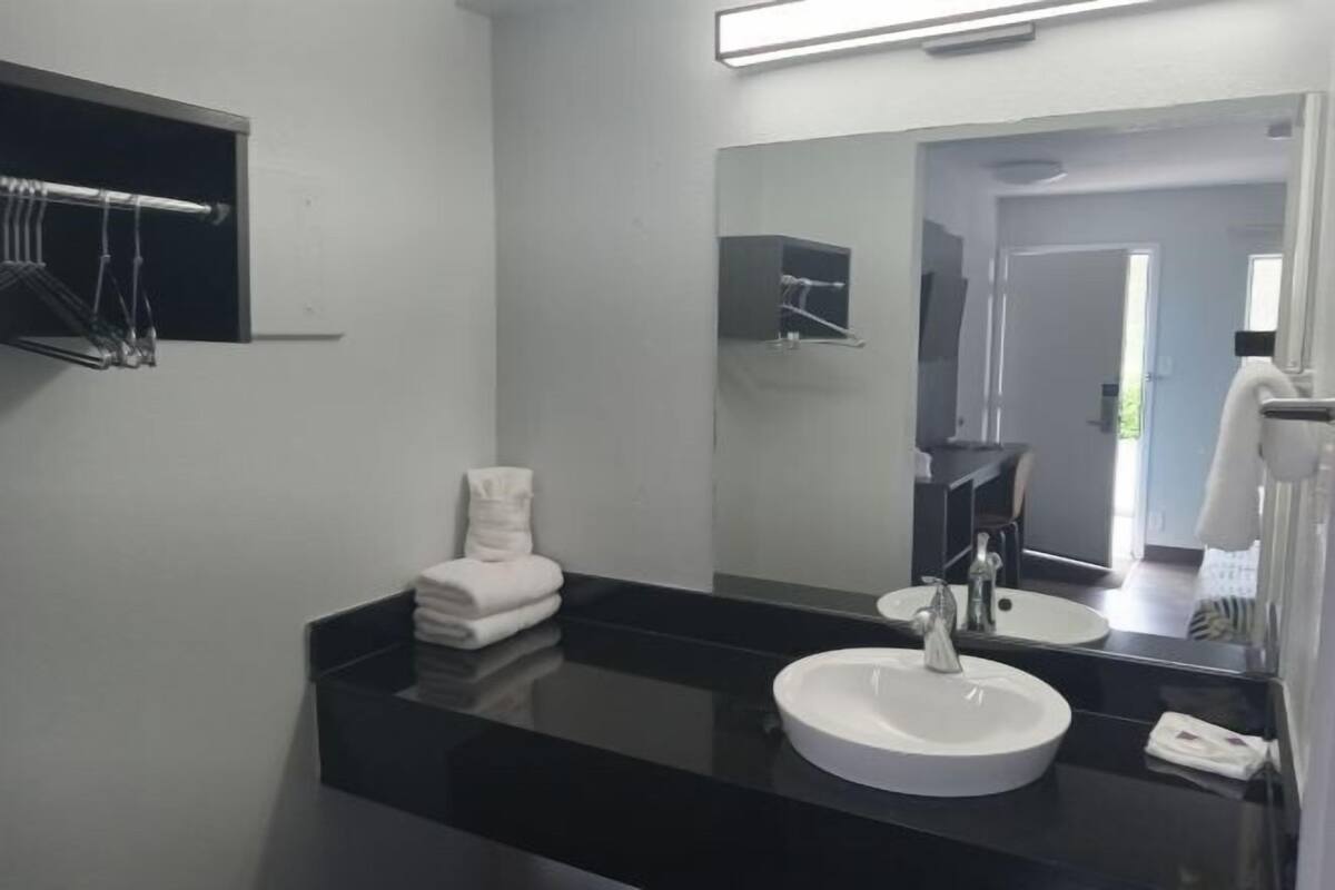 Een moderne badkamer met een zwart aanrechtblad, een witte wastafel, een spiegel en een handdoekrek.
