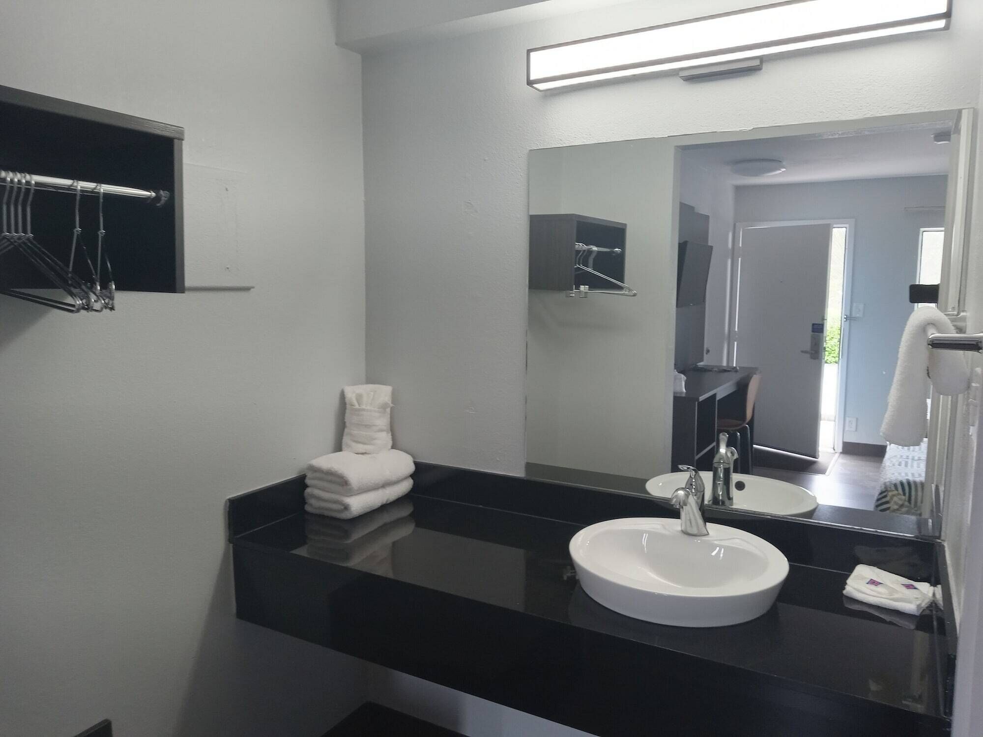 A modern bathroom with a black countertop, white sink, and a large mirror.