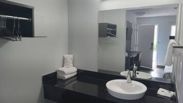 A modern bathroom with a black countertop, white sink, and a large mirror.