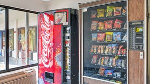 A vending machine with a Coca-Cola logo and a snack vending machine with various snacks. - Motel 6 Dalton, GA (Dalton)