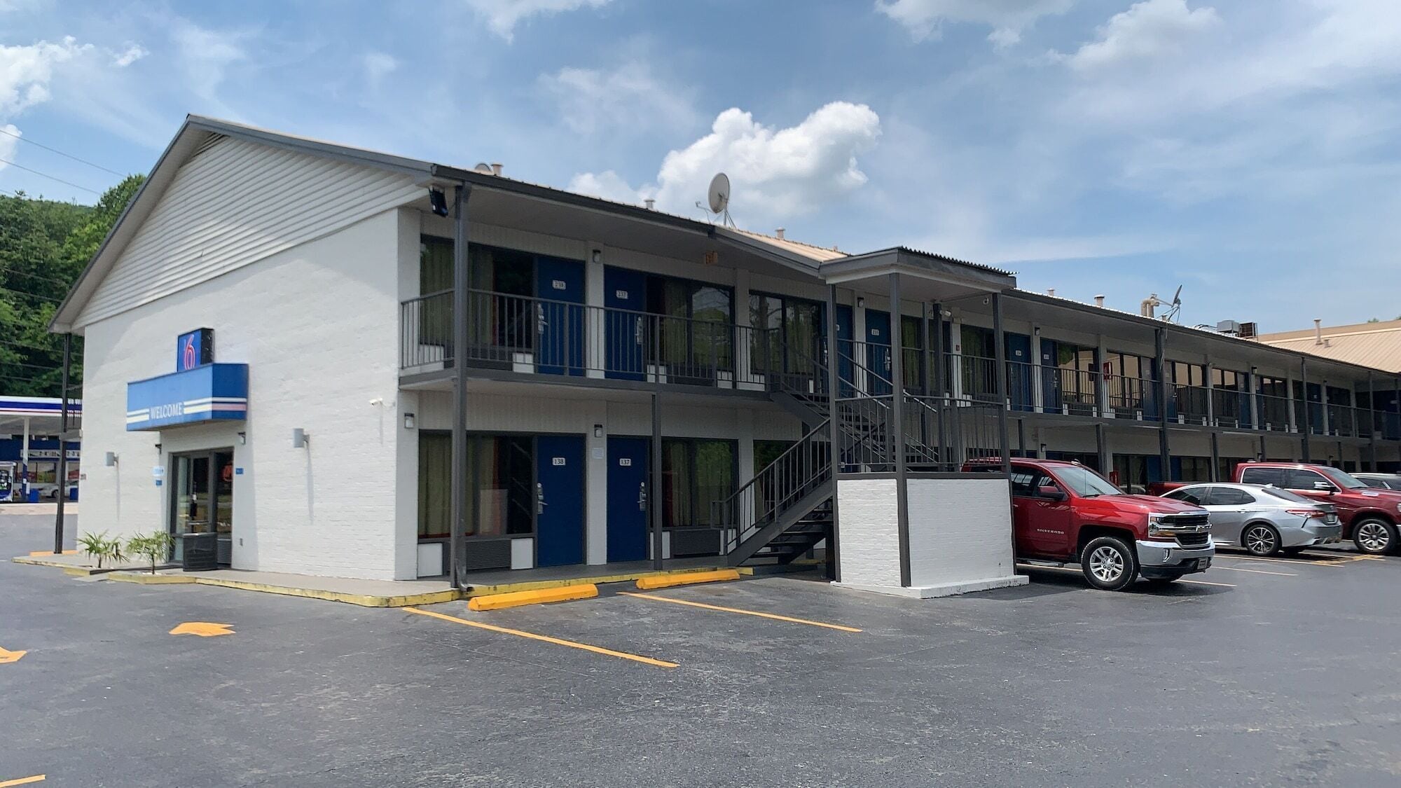 A motel with a two-story structure, multiple rooms, and a parking area with several cars.