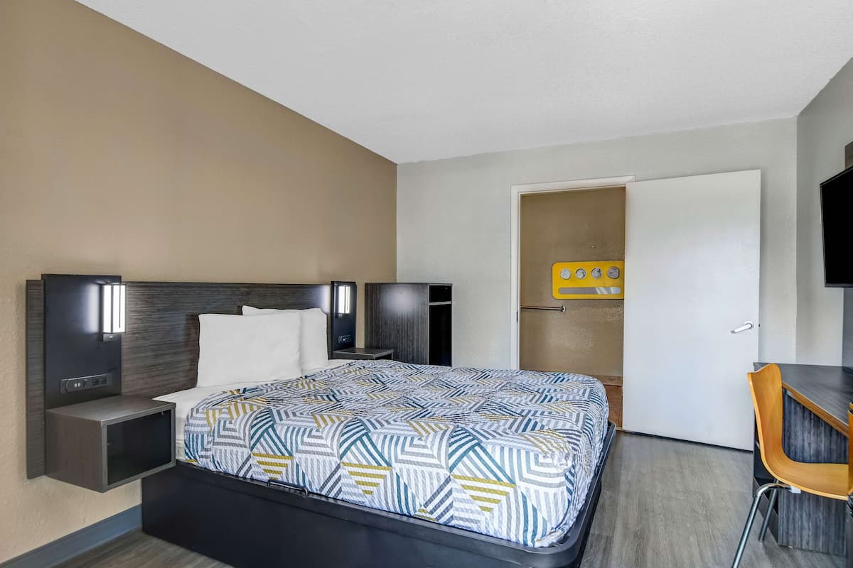 A hotel room with a bed, bedside tables, a desk, and a chair.