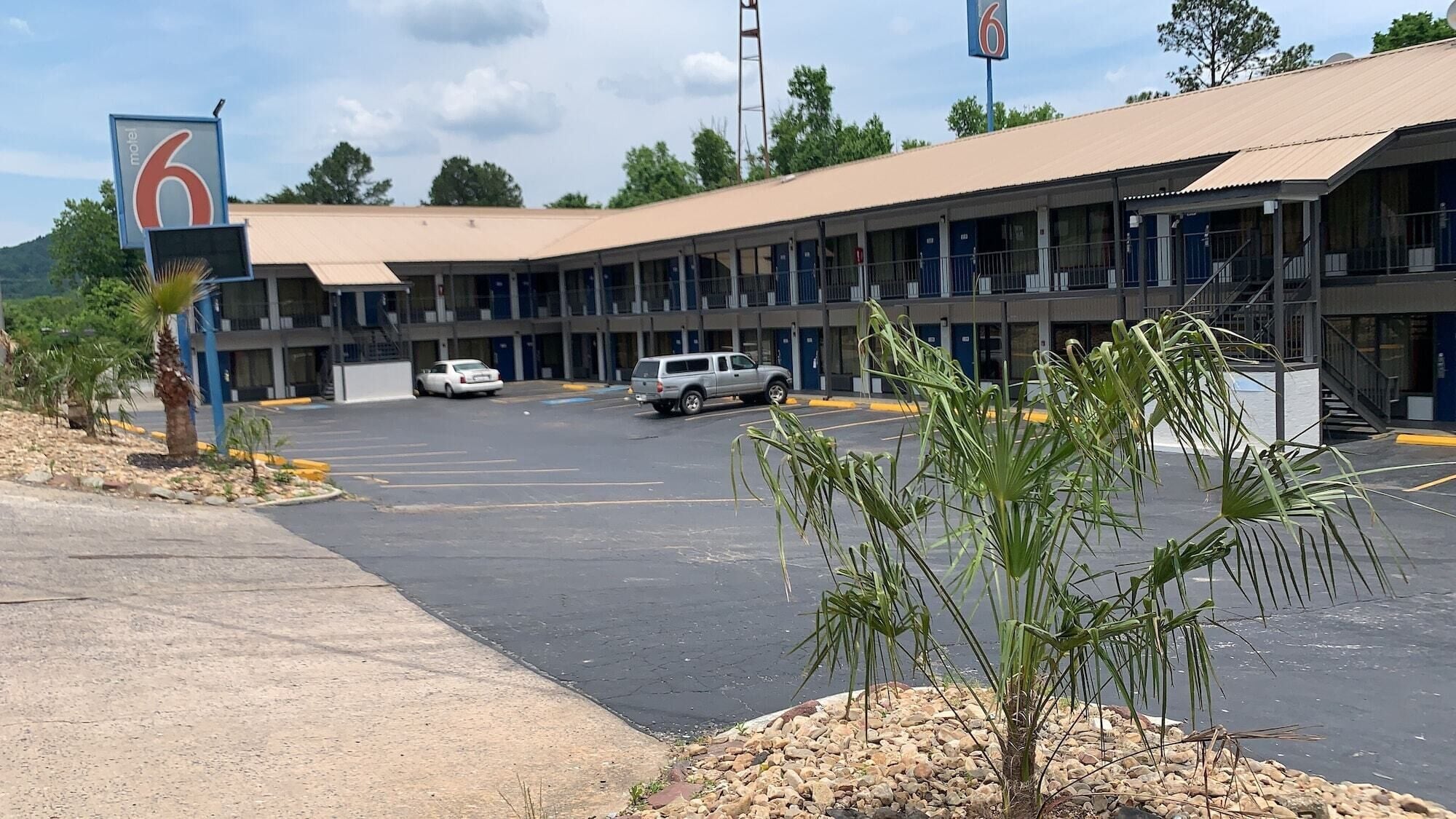 Um motel com estacionamento, um edifício térreo e uma placa indicando o número 6.