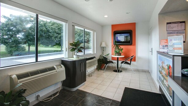 A modern hotel reception area with a large window, a digital display, and a Wi-Fi sign. - Motel 6 Elkton, MD (Elkton)
