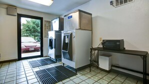 A compact kitchenette with a microwave, a refrigerator, and a washing machine. - Motel 6 Elkton, MD (Elkton)