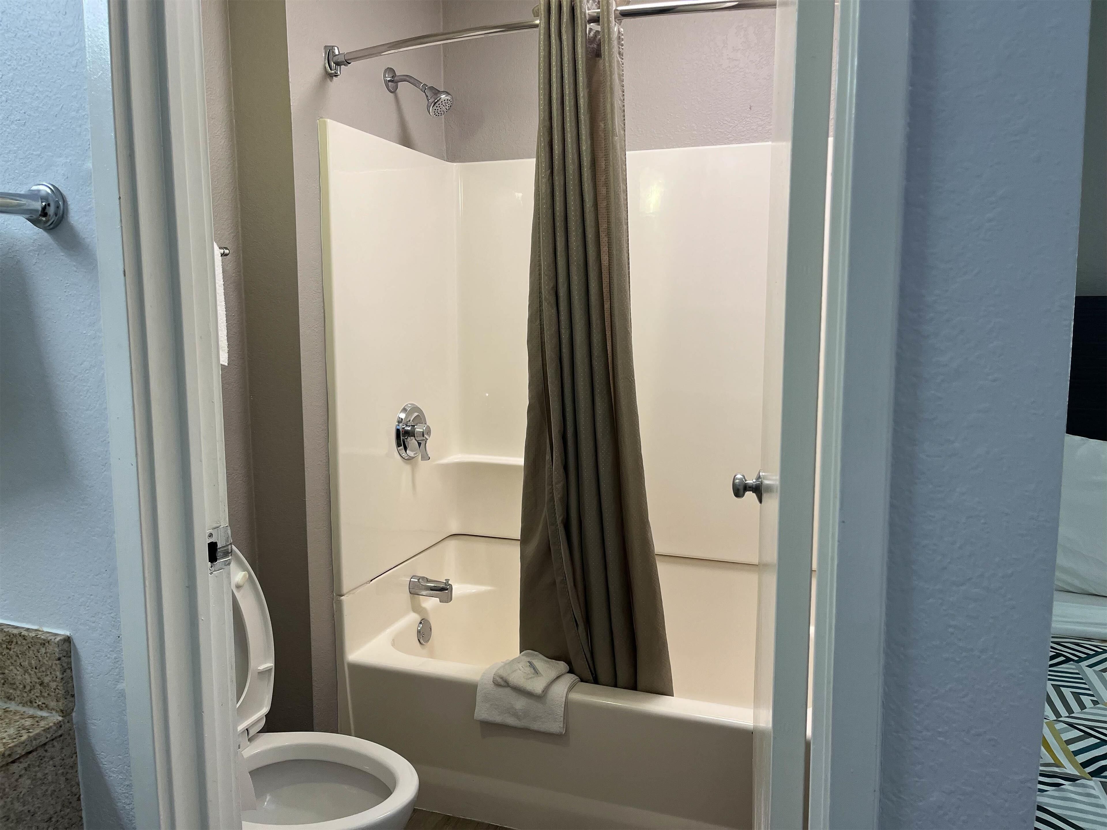 A corner bathroom with a toilet, a bathtub, and a shower.