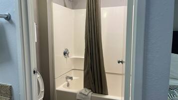 A corner bathroom with a toilet, a bathtub, and a shower.