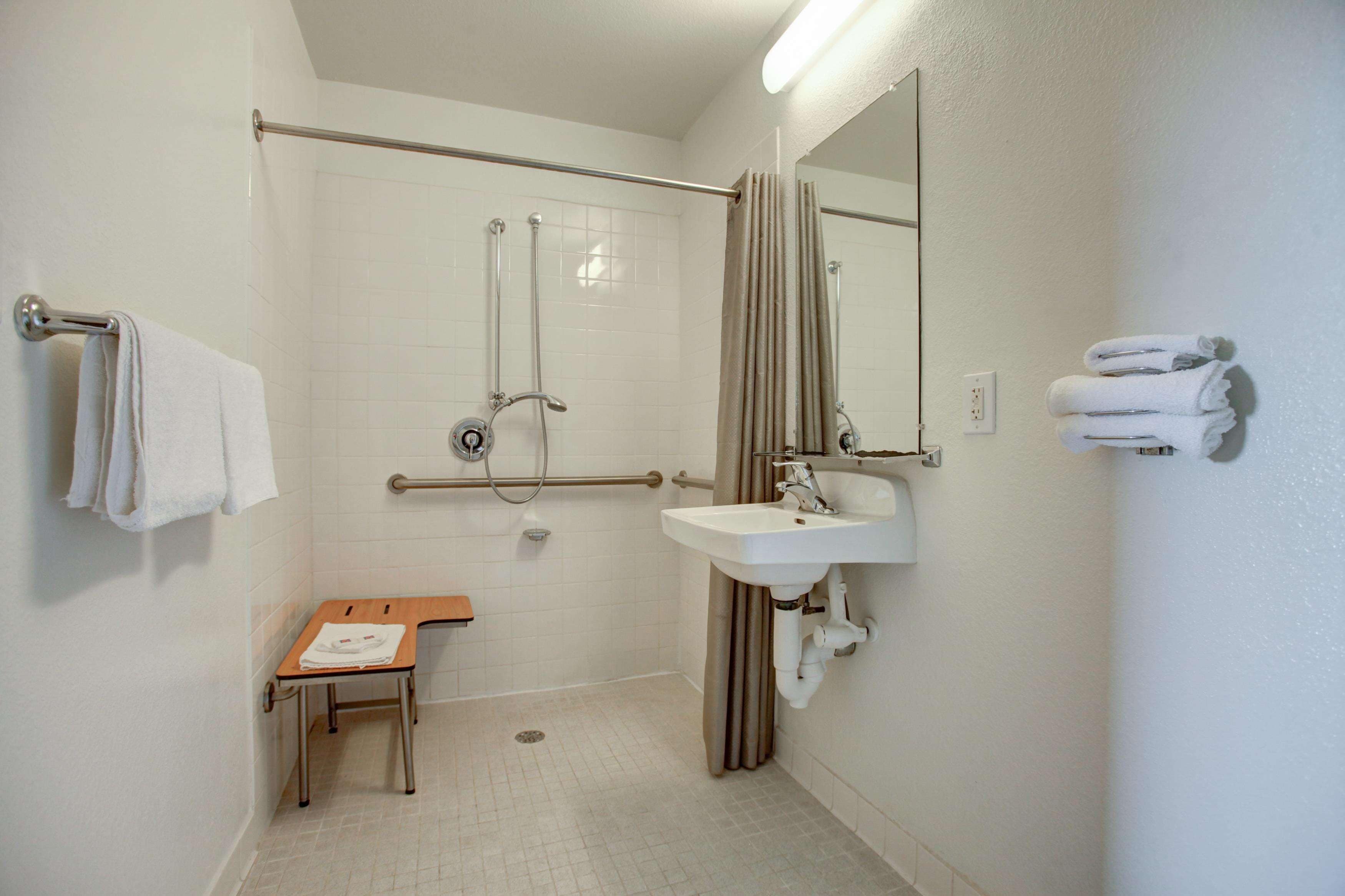A bathroom with a shower, a sink, a mirror, and a towel rack.