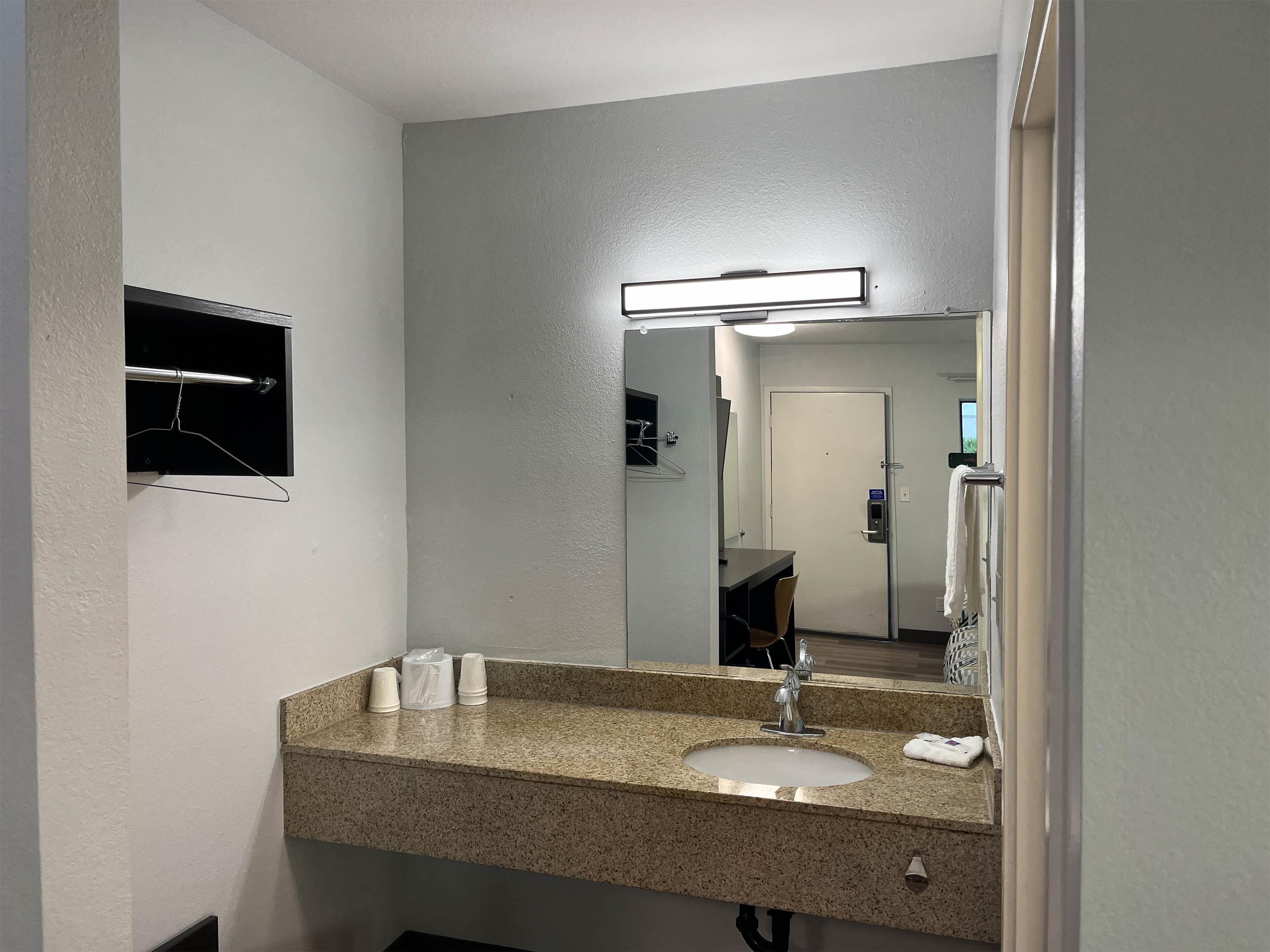 A bathroom with a granite countertop, a sink, a mirror, and a towel rack.