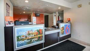 A reception desk with a sign stating "We'll leave the light on for you." - Motel 6 Elkton, MD (Elkton)